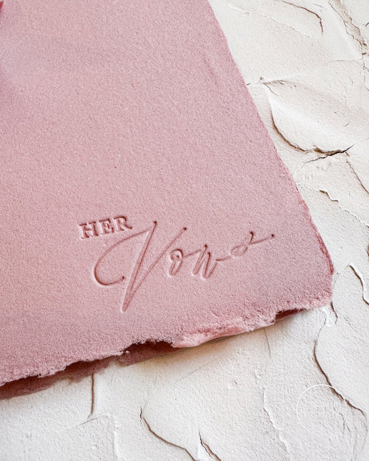 Pink handmade paper with 'HER Vows' branding on a textured white surface
